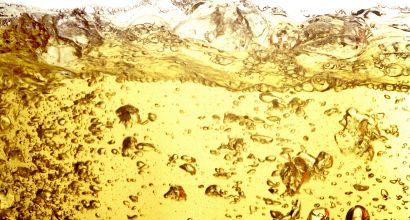 Close-up of liquid fuel in a golden hue with bubbles and movement, representing petroleum derivatives and energy