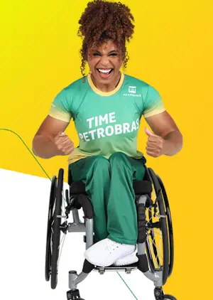 Mulher em cadeira de rodas, com uma camiseta escrito Time Petrobras, com expressão de garra.
