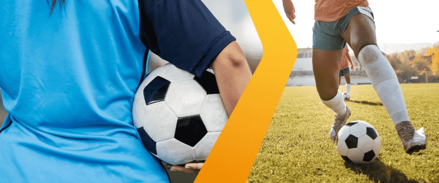 Duas jogadoras de futebol feminino: uma segurando uma bola com uniforme azul, e outra conduzindo a bola em campo gramado com uniforme rosa