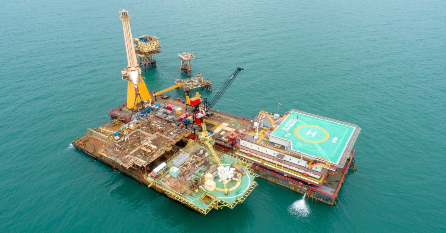 Aerial view of an offshore platform with helipad and drilling equipment at sea.