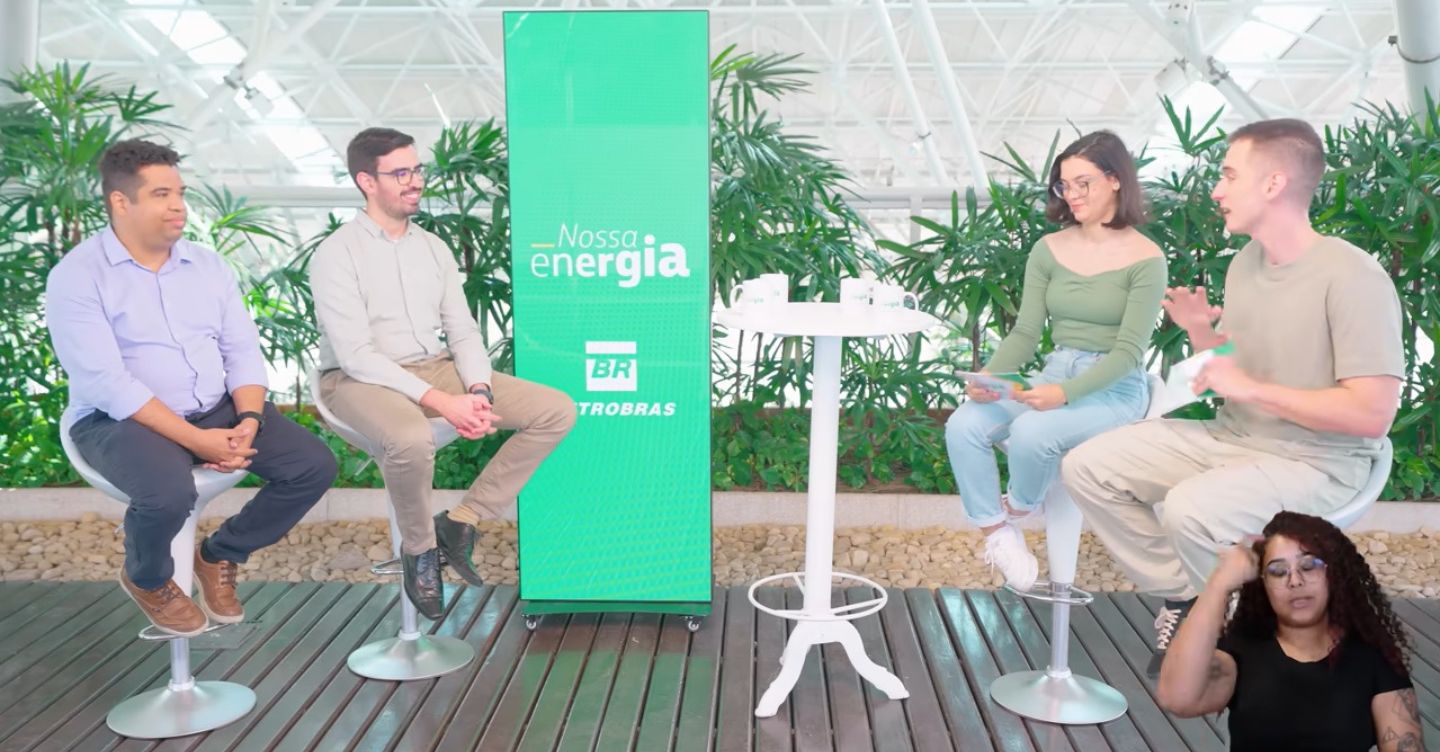 Quatro pessoas participam de conversa em um estúdio com painel “Nossa Energia Petrobras”, com intérprete de Libras no canto da imagem.