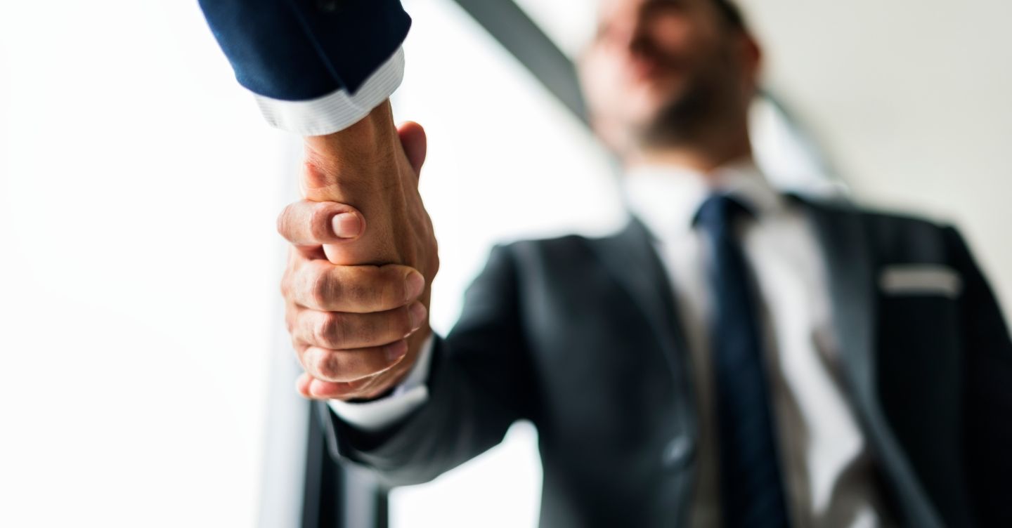 Close-up of a handshake between two people in formal attire, symbolizing a business agreement.