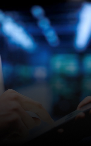 Hand interacting with a tablet with digital screens in the background.