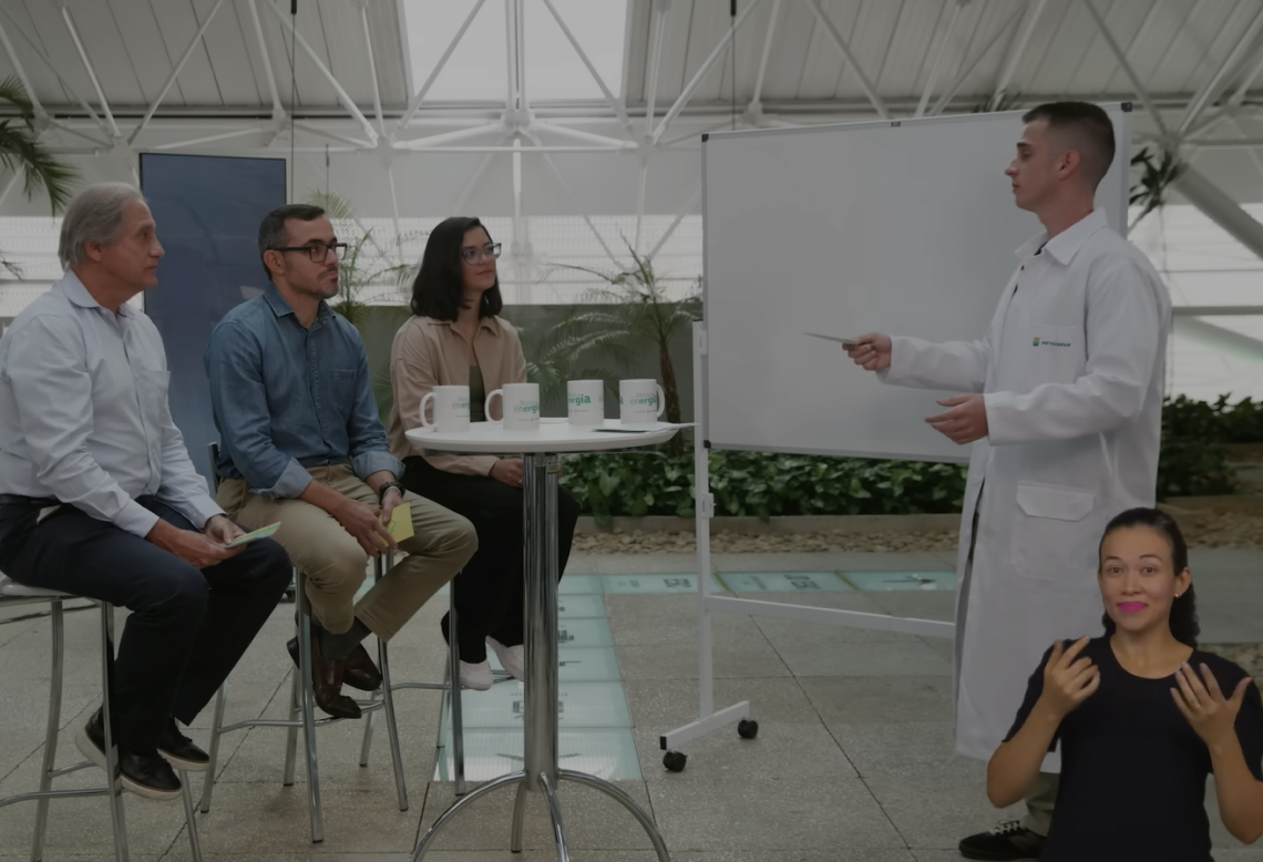Dois homens e uma mulher sentados em frente a um homem com jaleco branco.