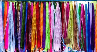 Fitas coloridas do Senhor do Bonfim penduradas lado a lado, cada uma com o texto "Lembrança do Senhor do Bonfim da Bahia" impresso.