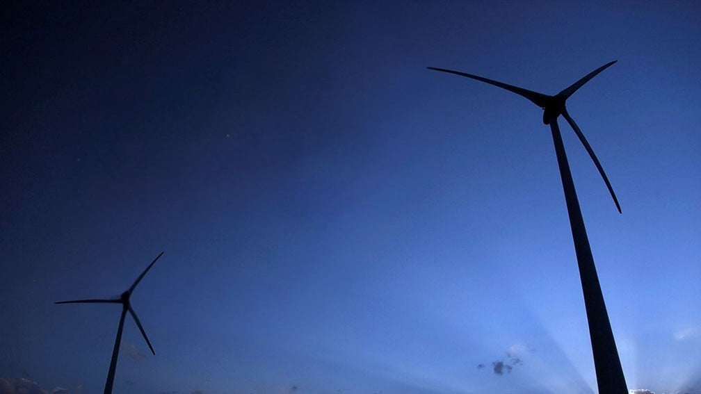 Silhueta de turbinas eólicas ao entardecer com texto "Transição Energética: tudo o que você quer e precisa saber".