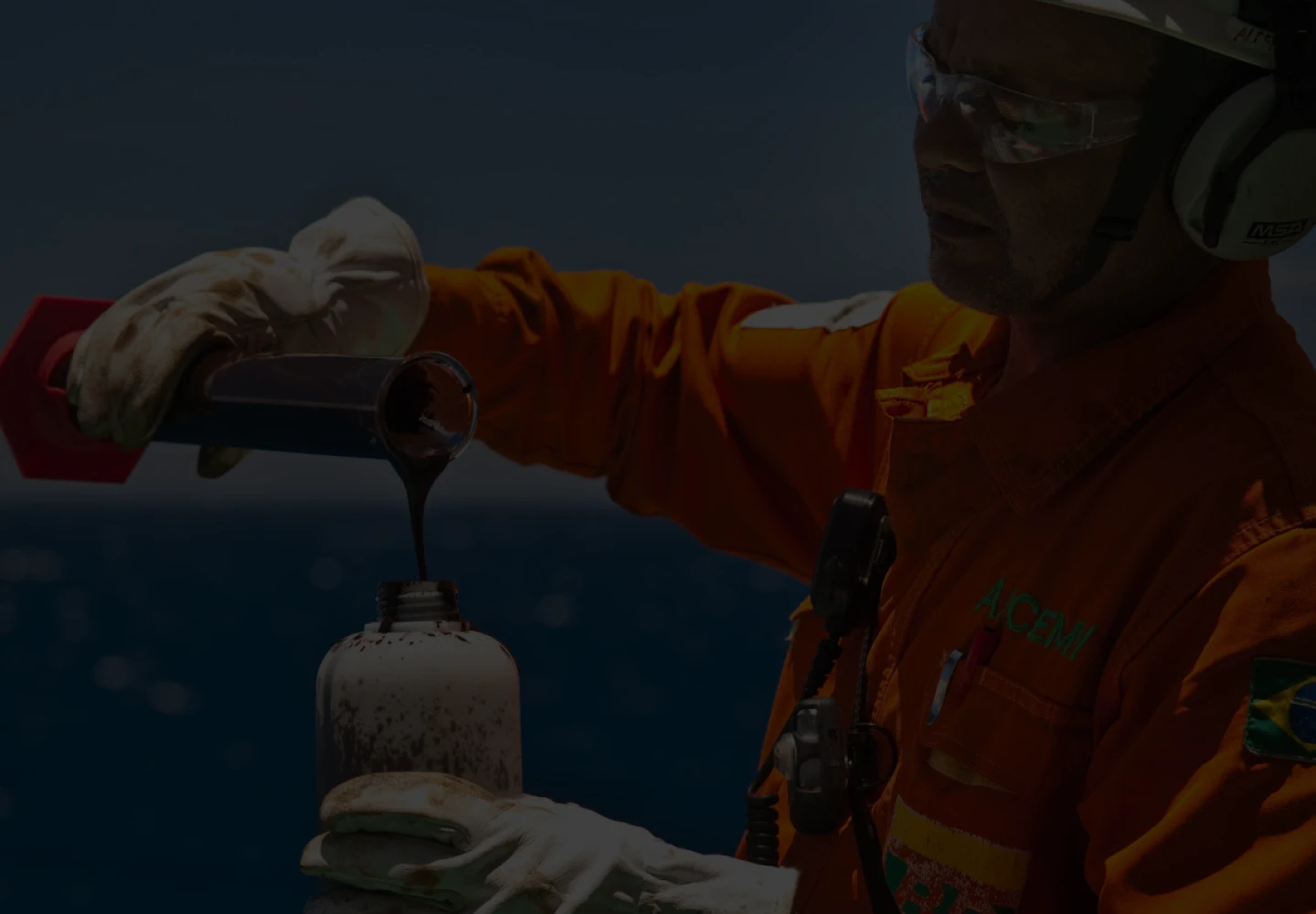 Fotografia de funcionário da Petrobras despejando petróleo em uma garrafa de metal.
