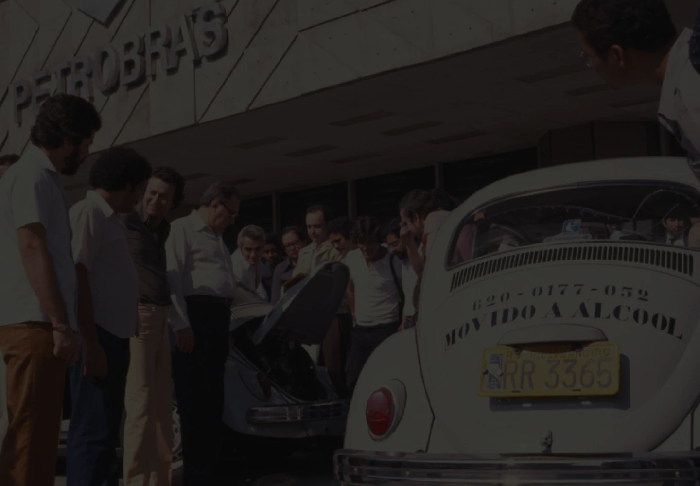 Old photo of people watching two VW Beetles in front of Petrobras’ headquarters. In one of them, it is written “Powered by ethanol”.