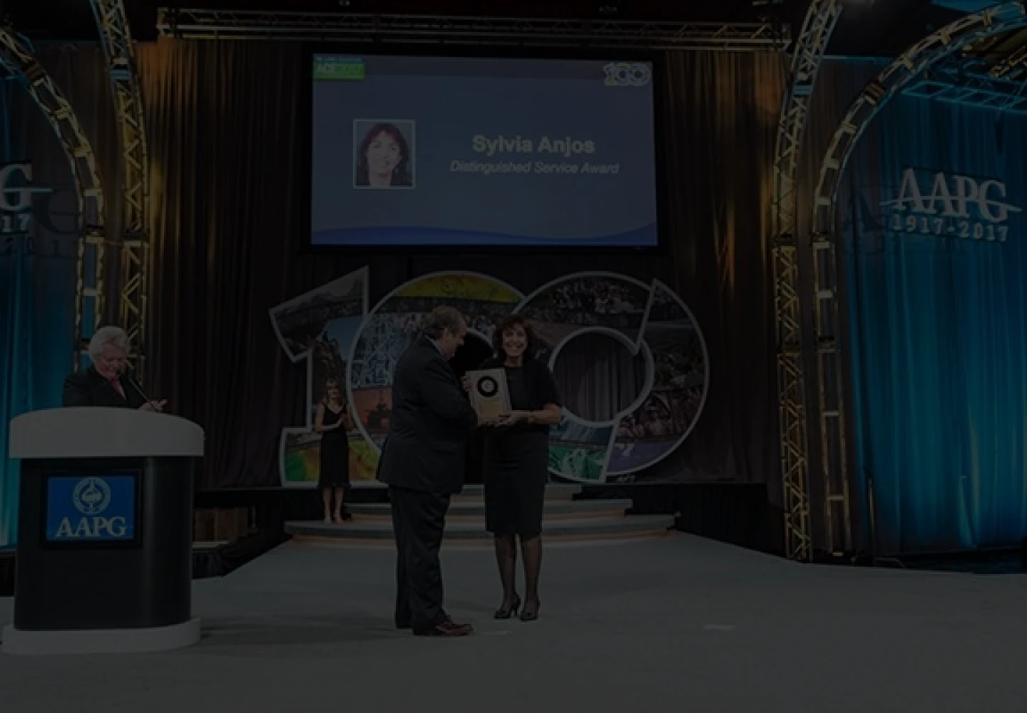 Fotografia da Sylvia Anjos, geóloga da Petrobras, recebendo o prêmio AAPG Distinguished Service Award.