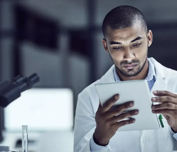 Funcionário de estágio da Petrobras em um laboratório, com um tablet em mãos.