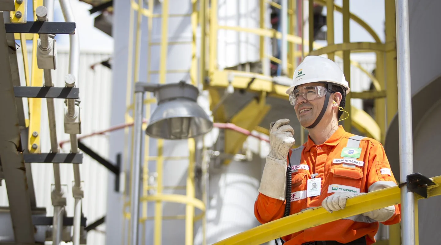 Petrobras employee talking into a walkie talkie, wearing full protective equipment.