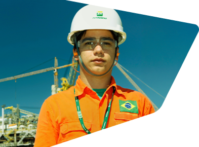 Employee with a career at Petrobras smiles at the camera, wearing uniform and full protective equipment.