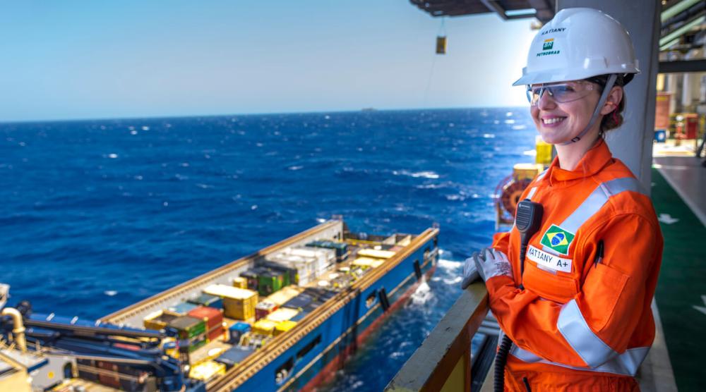 Funcionária com carreira na Petrobras em uma plataforma offshore, usando equipamento de proteção completo.