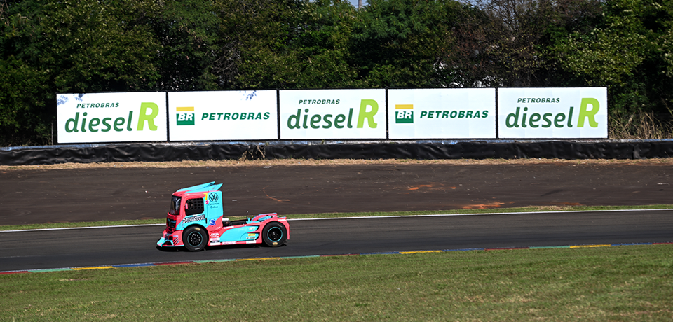 caminhão rosa e azul em pista de corrida com placa de diesel R e Petrobras