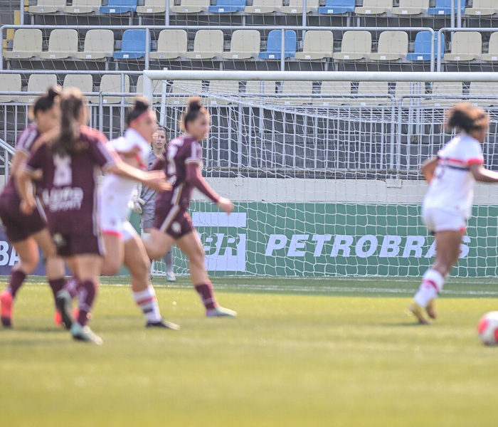 Mulheres jogando uma partida de futebol em um campo aberto.