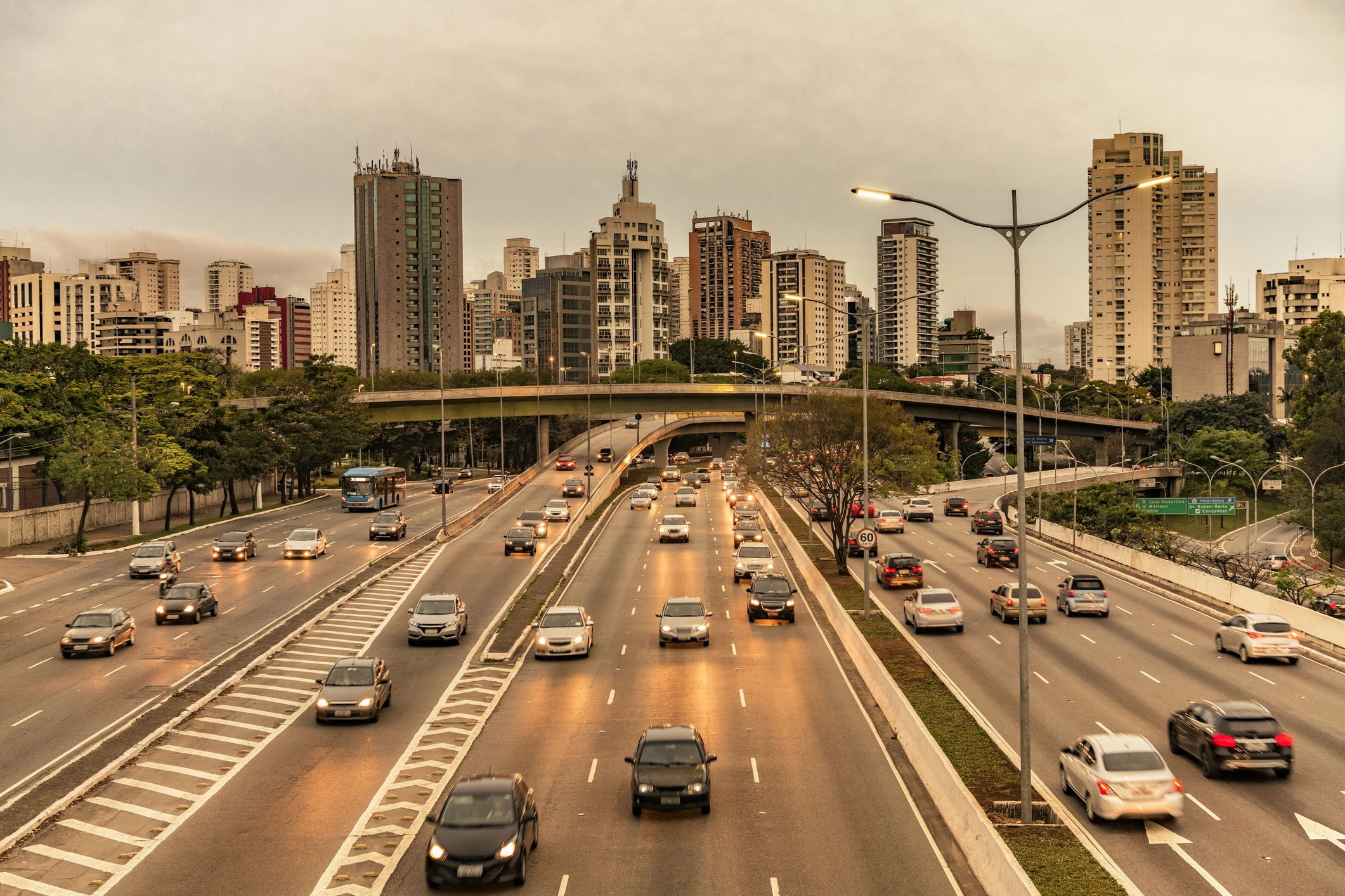 Foto de autoestradas repletas de automóveis, em frente a uma grande cidade, representando o uso de Gasolina Petrobras.