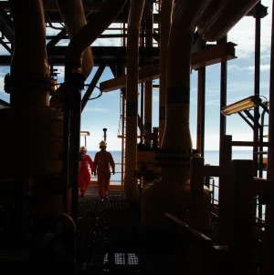 Photograph of Petrobras employees walking on an offshore Petrobras platform in the middle of the ocean.