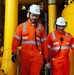 Colaboradores Petrobras vestindo EPIs de segurança enquanto trabalham em refinaria.