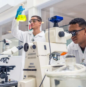 Dois jovens aprendizes da Petrobras interagem e analisam produtos em laboratório do Cenpes.