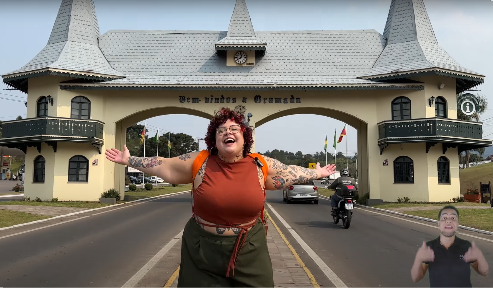 mulher sorrindo de braços abertos na entrada da cidade de gramado.