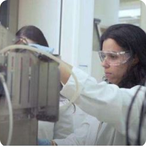 Cientista da Petrobras, com jaleco branco e óculos de proteção, utilizando equipamento do Cenpes.