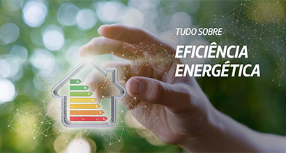 Uma mão aberta num momento de que irá pegar algo. Entre os dedos, há uma ilustração do contorno de uma casa com os selos de eficiência energética, de A a G, dentro dela.