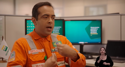 Homem dentro de um escritório usando uniforme laranja da Petrobras.