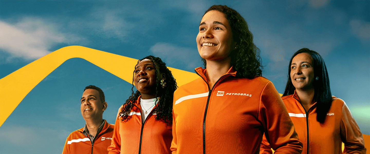 Group of Petrobras employees wearing orange uniforms, standing confidently against a blue sky.