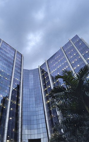 Glass-fronted Petrobras headquarters building (Edisen) at dusk, with palm trees in the foreground.