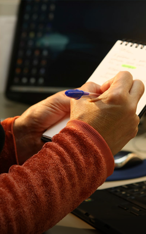 Close-up of a person's hands taking notes on a notepad.