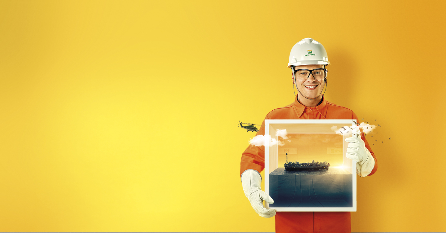 homem com uniforme da Petrobras segurando uma imagem de uma plataforma.