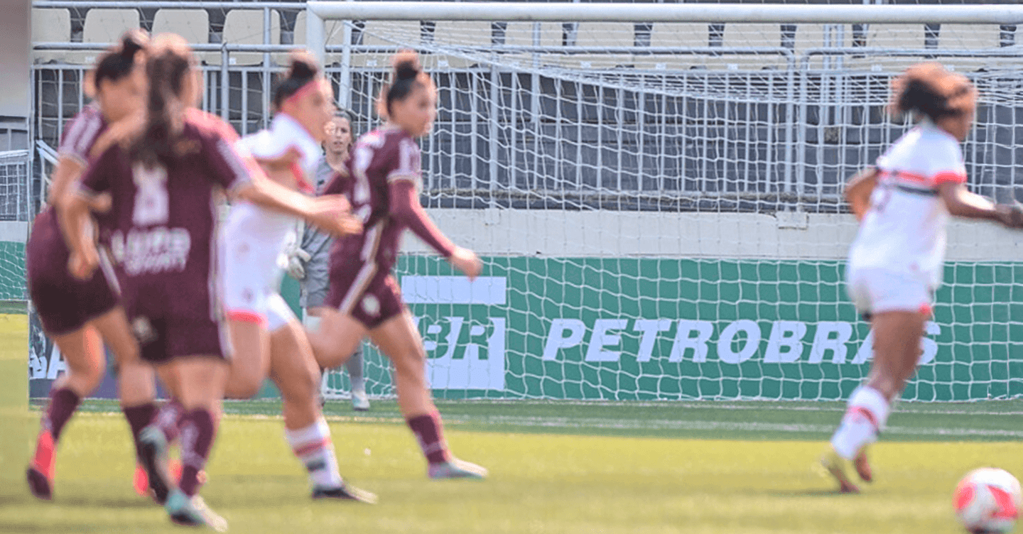 Women playing football with Petrobras sign in the background.