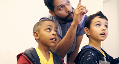 Bearded man points something to two children