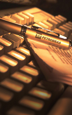 Pen with Petrobras logo on a sheet of paper and keyboard.
