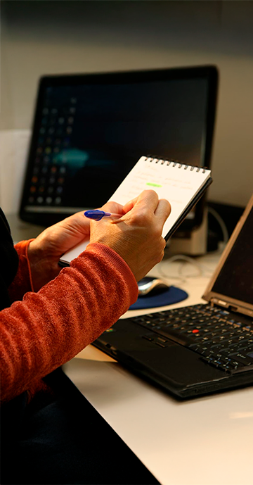 Woman taking notes on a pad in front of a notebook.