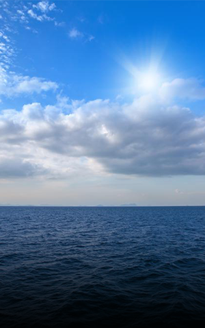 Fotografia diurna do horizonte entre o oceano e um céu com nuvens.