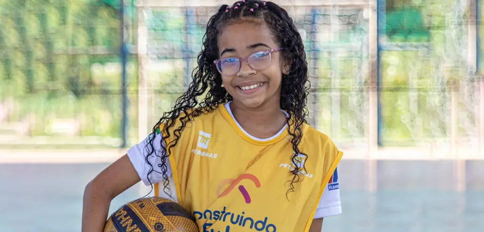 menina de óculos segurando uma bola de futebol