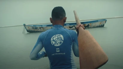 Man in Coral Vivo project attire holding an oar and walking towards a boat.