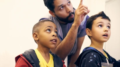 An adult pointing at something while talking to two children.