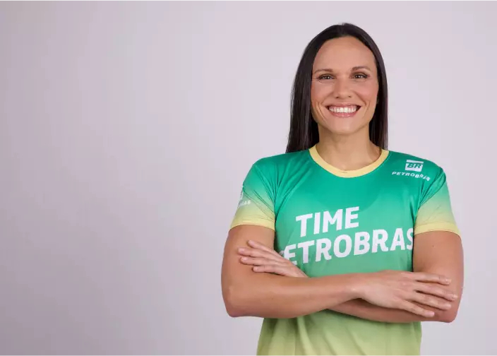 Mulher com os braços cruzados vestindo camiseta com escrito Time Petrobras.